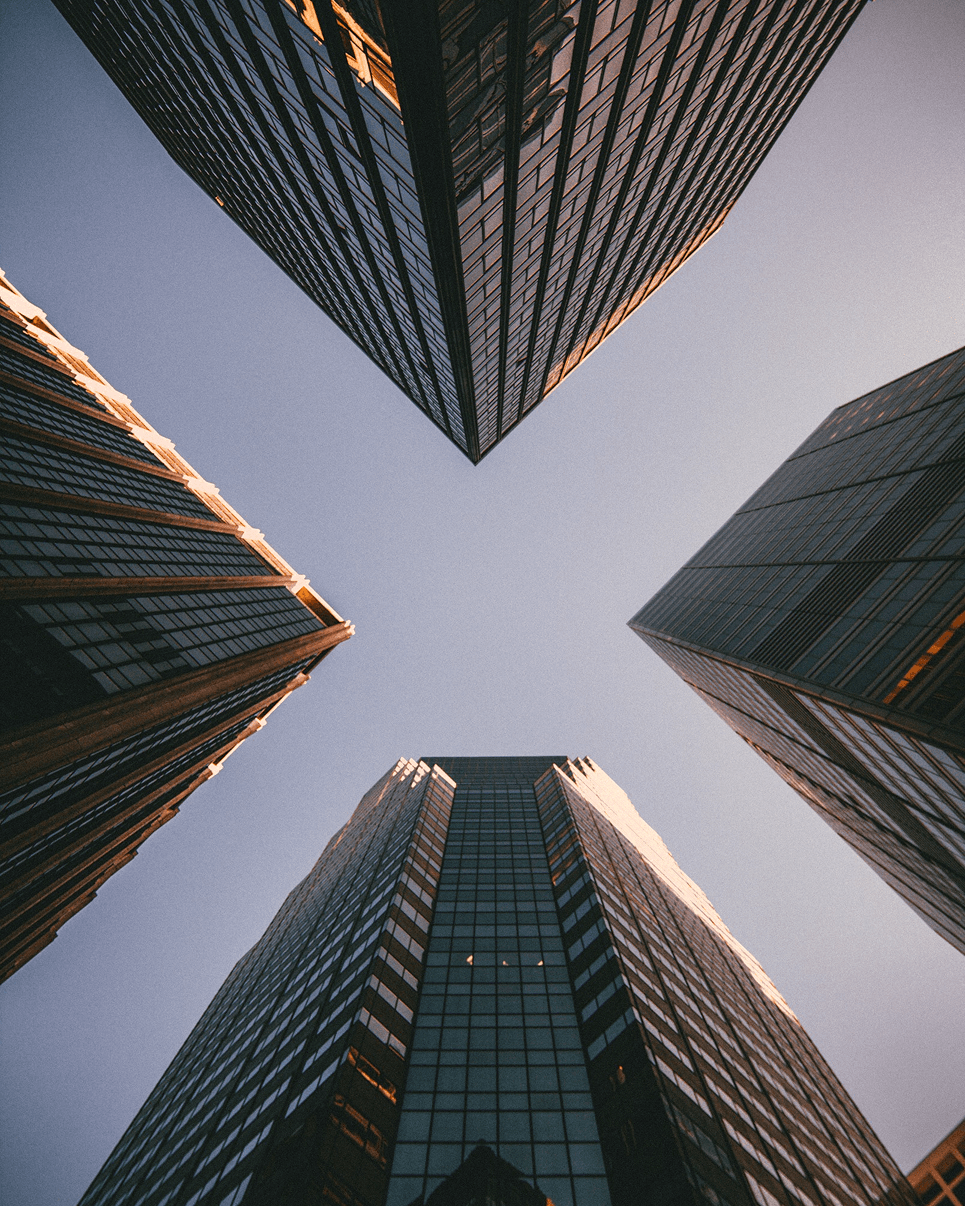 Looking up at a cluster of glass skyscrapers against the sky
